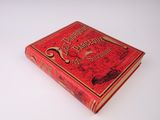 un vieux livre rouge posé sur une table blanche