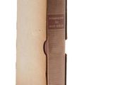 an old book with a brown cover sitting on top of a white surface