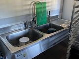 stainless steel sink in a commercial kitchen with a ladder in the background