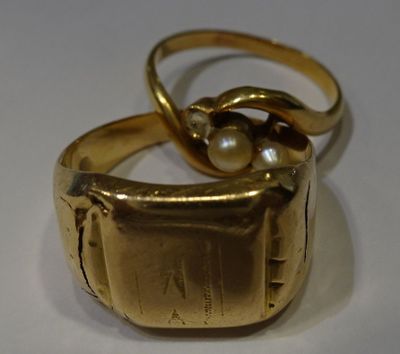 a gold ring with a pearl in it on a white surface
