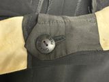 the back of a black jacket with a button on it
