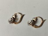 two pairs of gold and silver earrings on a white surface