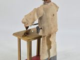 wooden toy of a man in a white coat and hat working on a piece of wood