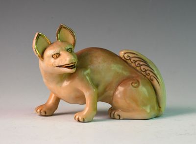 une figurine représentant un chat assis sur une surface blanche