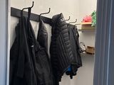 three coats hanging on a rack in a small room