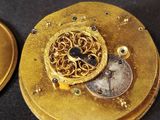 a close up of a gold clock with a coin on it