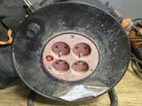 un ventilateur noir posé sur une table, à côté d'une paire de bottes