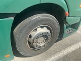 a green bus with a flat tire parked on the side of the road