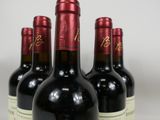 six bottles of red wine are lined up on a table