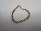 gros plan d'un bracelet en chaîne en or sur une surface blanche