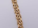 a close up of a gold chain bracelet on a white surface