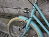a blue bicycle leaning against a wall with a basket on it