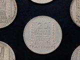 six different types of silver coins on a black surface