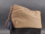 the hat is tan and has a tassel on it