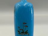 a blue vase with flowers painted on it on a table