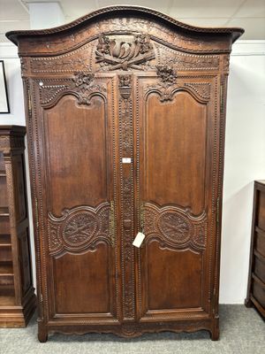 une photo d'une grande armoire en bois dont les portes sont ornées de sculptures