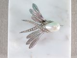 silver dragonfly brooch with pearl and diamonds on white marble