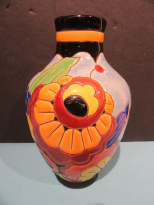 a vase with a flower painted on it sitting on a table
