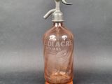 a pink glass bottle with a metal handle on a gray surface