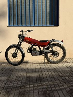 a red motorcycle parked next to a building with a blue window