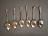six silver spoons are lined up in a row on a table