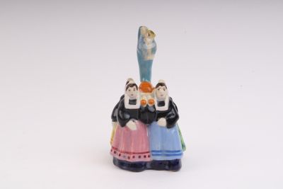 a figurine of a group of people on top of a bell