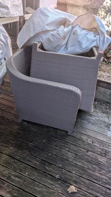 deux chaises en osier posées sur une terrasse et recouvertes de housses