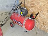 a red air compressor sitting on a cart in a garage