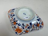 a small blue and orange vase on a white table