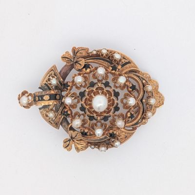 une broche en or ornée de perles, posée sur un fond blanc