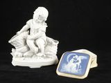 une petite figurine représentant un garçon assis sur une pile de livres, à côté d'une bague