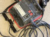 a red and black corded device sitting on the floor next to a mouse