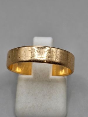 un gros plan d'une bague en or posée sur un socle blanc