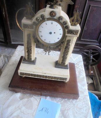 une petite horloge posée sur une table, sur laquelle est posée une note