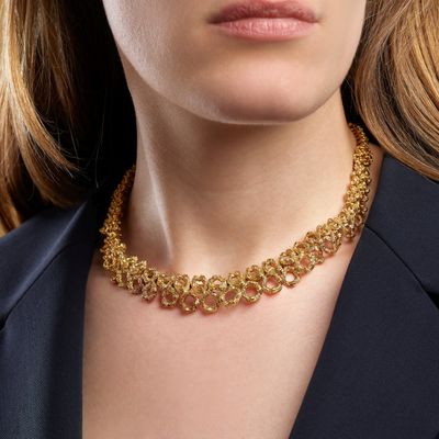 La femme porte un collier en or et une veste noire.