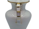 a white vase with a gold handle on a white background