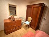 a teddy bear sitting on top of a dresser next to a chair