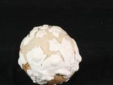 a white and brown ball of frosting on a black surface