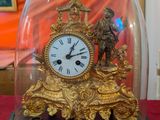 a gold clock under a glass dome on a red table
