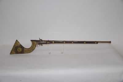 an old gun with a wooden handle on a white surface