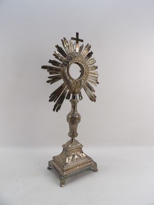 une statue en argent représentant un soleil surmonté d'une croix