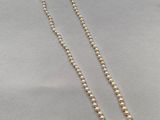 un collier de perles blanches avec un fermoir en or sur fond blanc