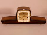 une horloge en bois avec un cadran blanc posée sur une table