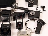 many different types of cameras and accessories laid out on a white surface