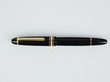 un stylo plume noir et doré posé sur une surface blanche