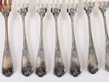 five forks and six spoons on a white surface