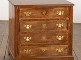 une commode ancienne en bois avec des poignées en laiton, posée sur un parquet