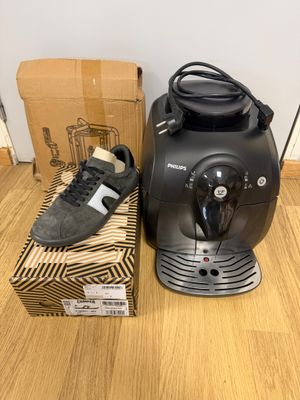 the coffee machine is next to a box of shoes on the floor