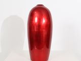 a shiny red vase sitting on a white table