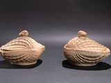 une paire de coquillages sculptés posés l'un sur l'autre sur une surface noire